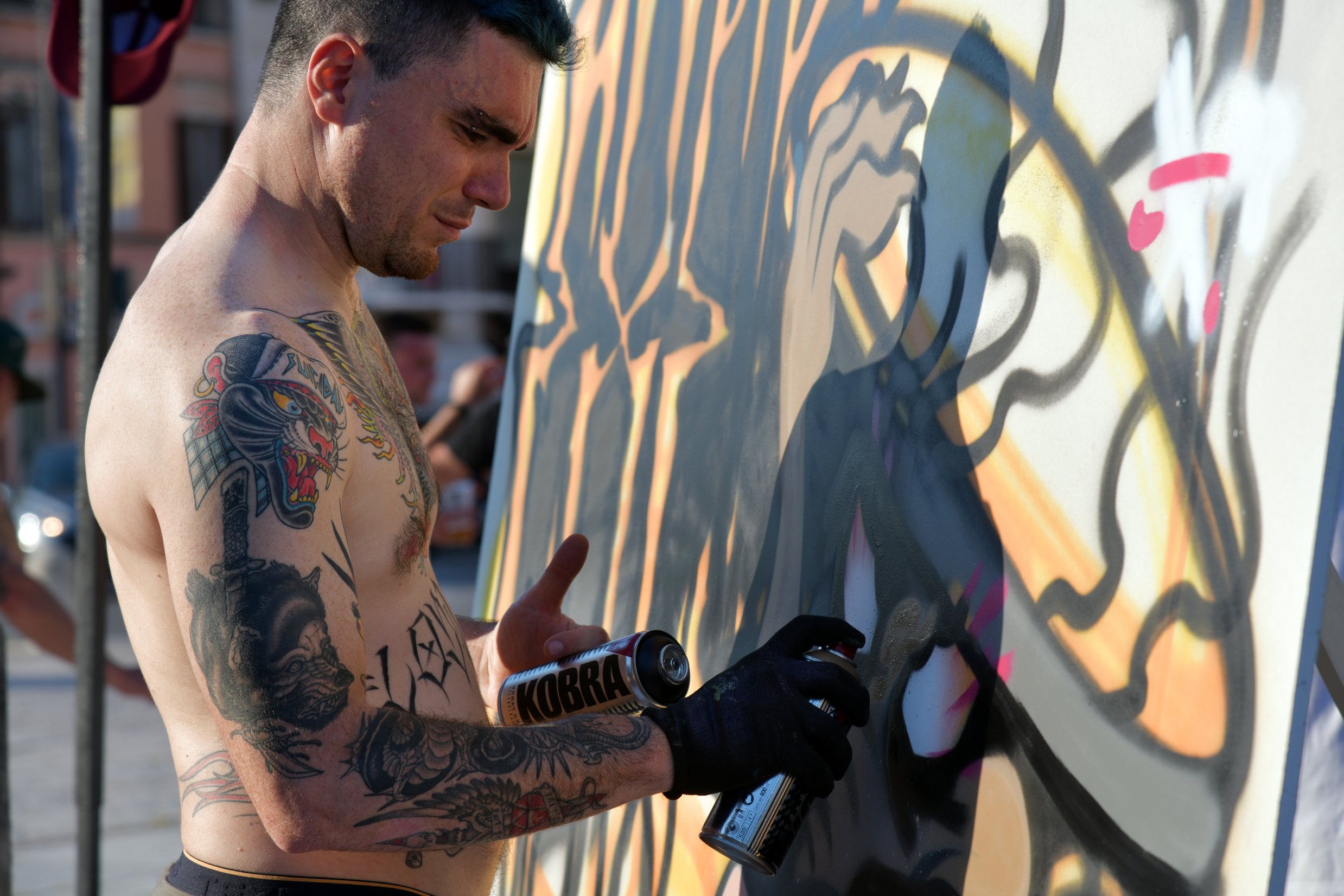 Side View Photo of Topless Tattooed Graffiti Artist Painting Wall